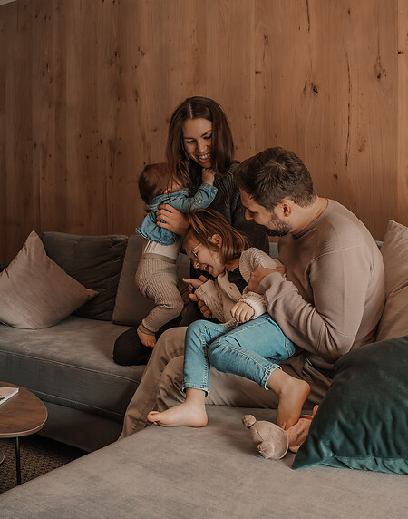 Familie sitzt in einer Familien Suite mit Holzmaterialien auf der Couch