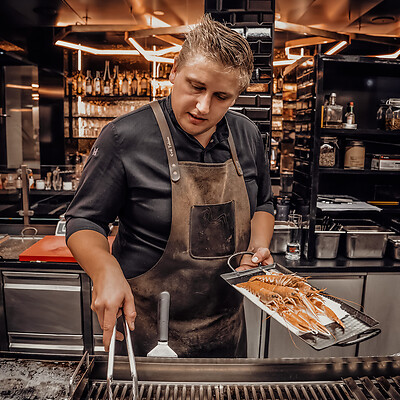 Haubenkoch grillt Garnelen in der offenen Schauküche im Steakrestaurant