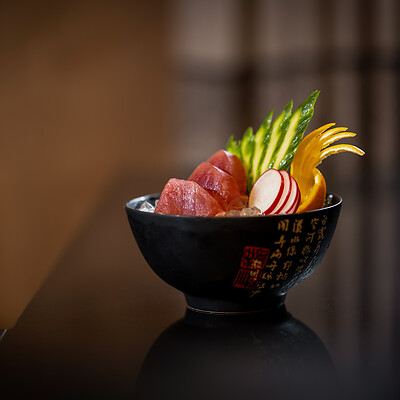 Asiatische Sushi Bowl auf schwarzer Platte mit Deko