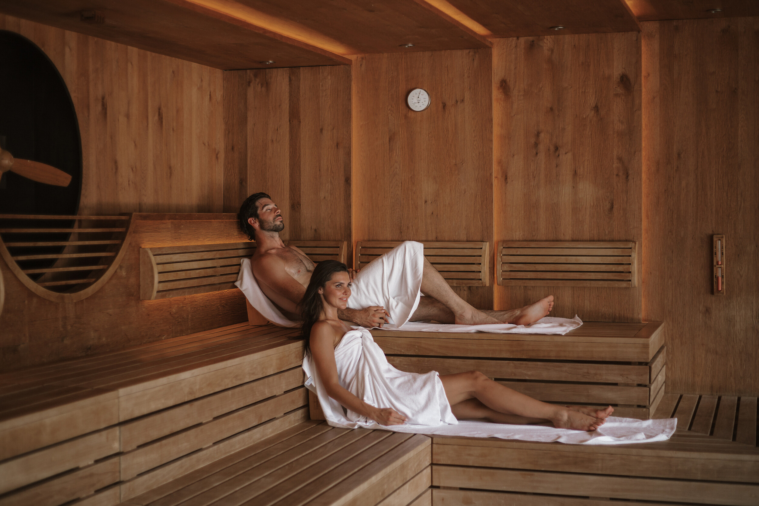 Paar sitzt und liegt in der Panorama Sauna mit Bergblick