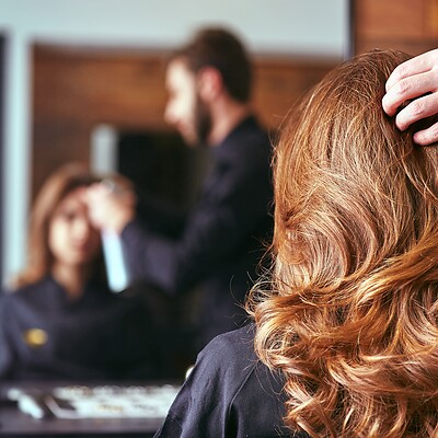 Gelockte braune Haare werden von Friseur gestylt