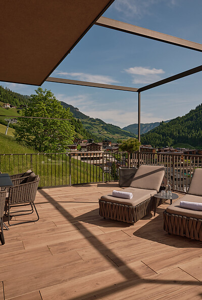 Privat terrasse med panoramaudsigt over Großarltal fra en eksklusiv suite på det 5 stjernede DAS EDELWEISS, omgivet af de østrigske Alper og grøn natur.