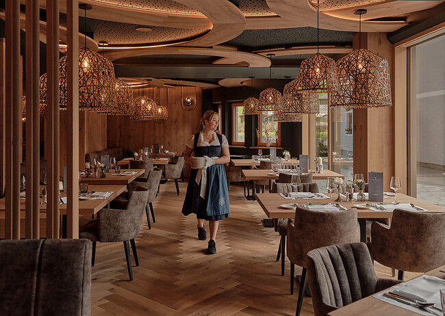 Service läuft mit Tellern im Sterne Restaurant in Großarl mit Holzverkleidung 