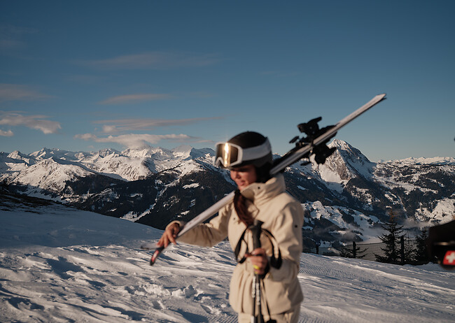 Frau trägt Skier aus dem Hotel mit Ski In Ski Out