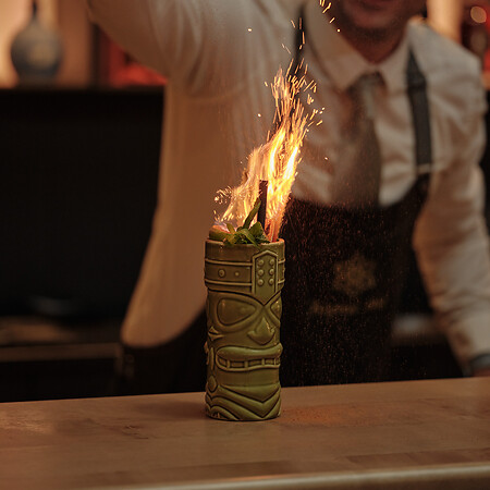 Bartender serves a cocktail in green glass with sparks