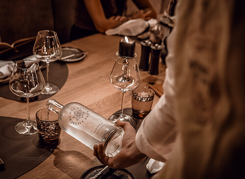 Service member pours water into a glass in the steak house Grossarl near Salzburg