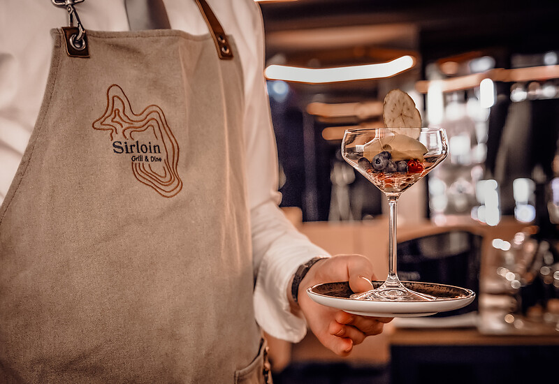 Service personnel carries dessert with champagne in hand