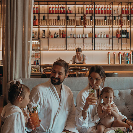 Family sitting in restaurant with bathrobe after swimming in the family hotel with pool