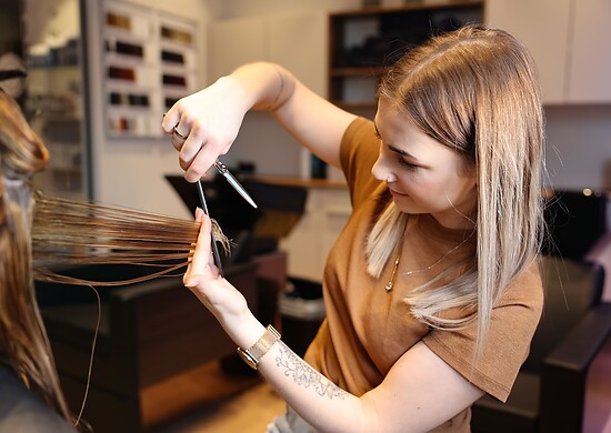 Hairdresser cuts woman's wet hair