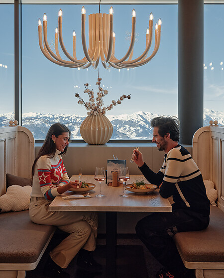 Couple sitting on a ski hut with panorama of the Sky Lounge Wolke 7