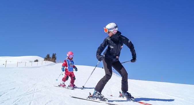 Elternteil fährt Ski mit Kind